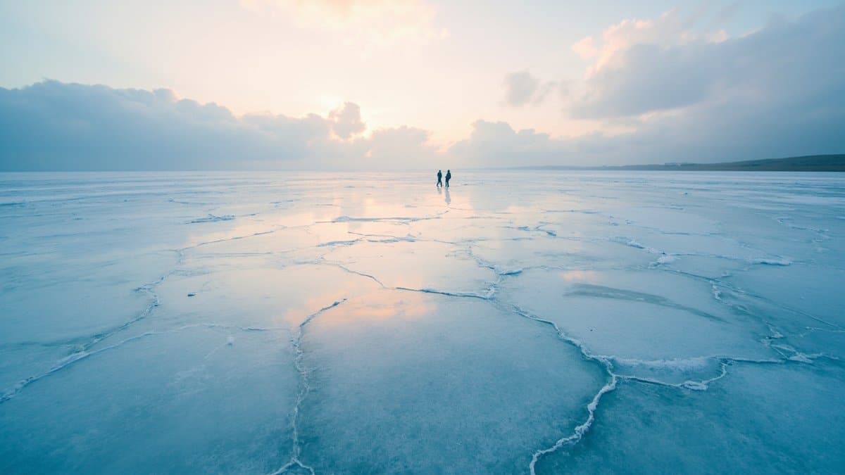unexplained mysteries 2026 - a frozen-over lake in Kazakhstan with refrozen glass-like plates across the surface at dawn
