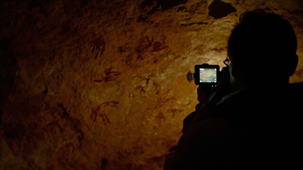 A dramatic photograph of ancient cave paintings being photographed by a researcher in a remote cave